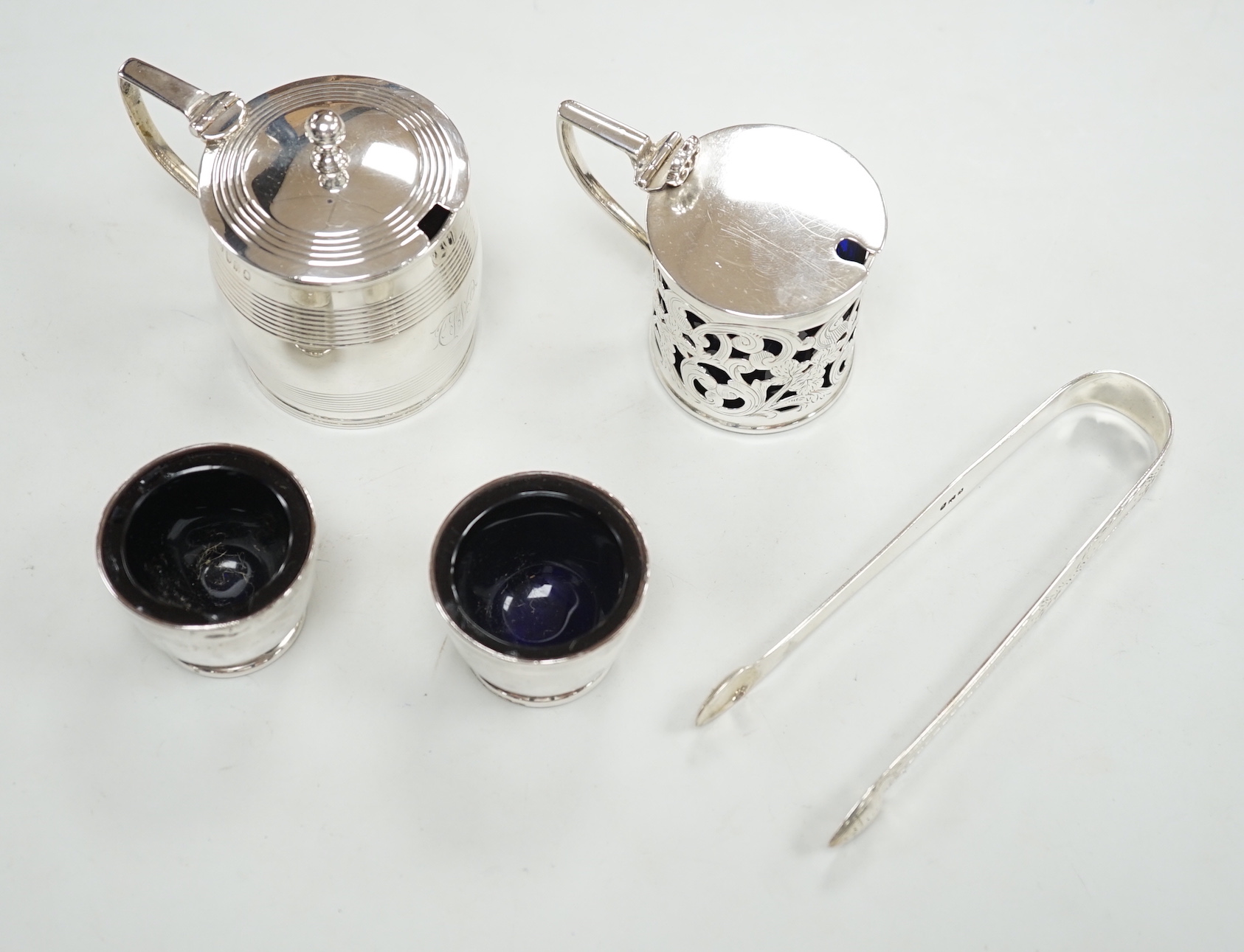 A George III reeded silver barrel shaped mustard pot, London, 1810, height 78mm, a later silver mustard, pair of silver salts and a pair of silver sugar tongs.